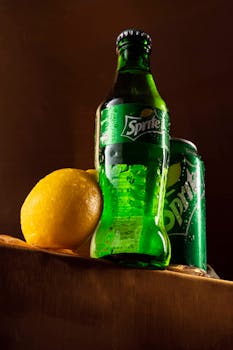 Sprite bottle and can with fresh lemon and water droplets for a vibrant visual.